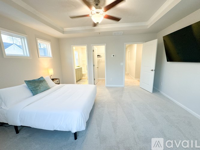 A bedroom with a bed, a ceiling fan, and a window.