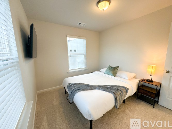 A bedroom with a bed, nightstand, and window.