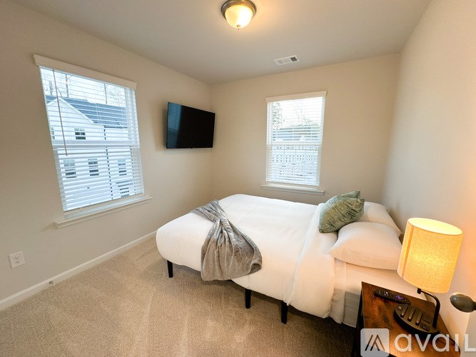 A bedroom with a bed, a lamp, and a flat screen TV mounted on the wall.