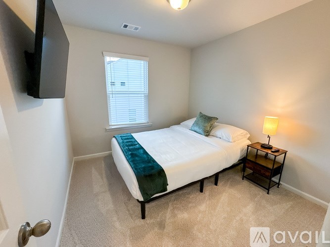 A bedroom with a bed, nightstand, and window.