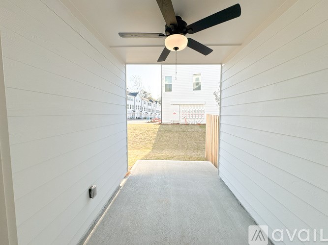 A white hallway with a ceiling fan and a window.