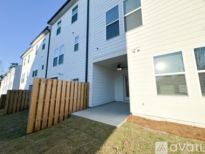 A white two-story apartment building with a wooden fence in front.