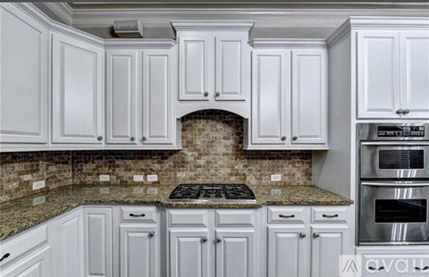 A kitchen with white cabinets and a granite countertop.