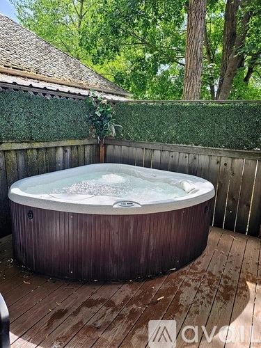 A hot tub on a wooden deck surrounded by a wooden fence.