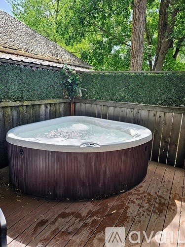 A hot tub on a wooden deck surrounded by a wooden fence.