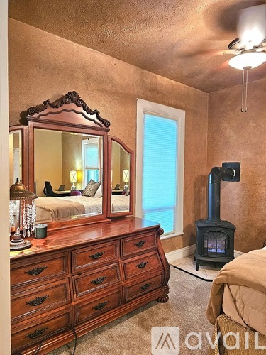 A bedroom with a wood dresser and a mirror.