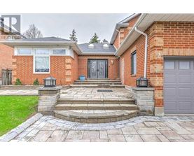 A red brick house with a black door and a stone walkway leading to it.
