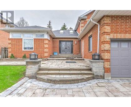 A red brick house with a black door and a stone walkway leading to it.