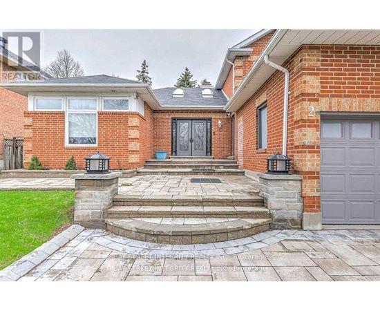 A red brick house with a black door and a stone walkway leading to it.