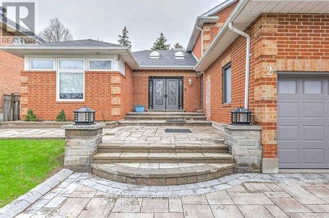A red brick house with a black door and a stone walkway leading to it.