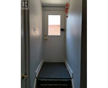 A hallway with a door and a sign that says Bay Street Integrity Realty Inc. Brokerage.