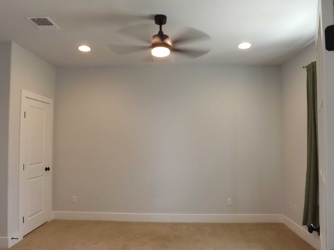 A room with a ceiling fan and a door.
