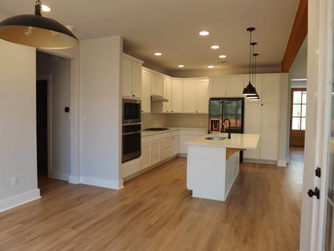 A kitchen with white cabinets and a wooden floor.