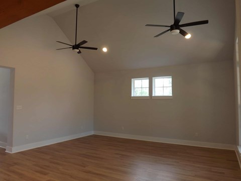 A room with wooden floors and a ceiling fan with two lights.