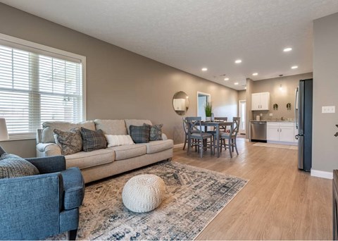 A living room with a couch, chairs, and a rug.