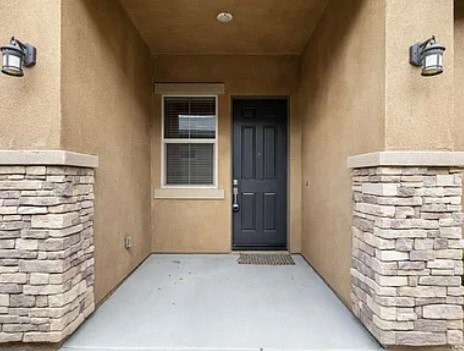 A black door is flanked by two stone pillars.