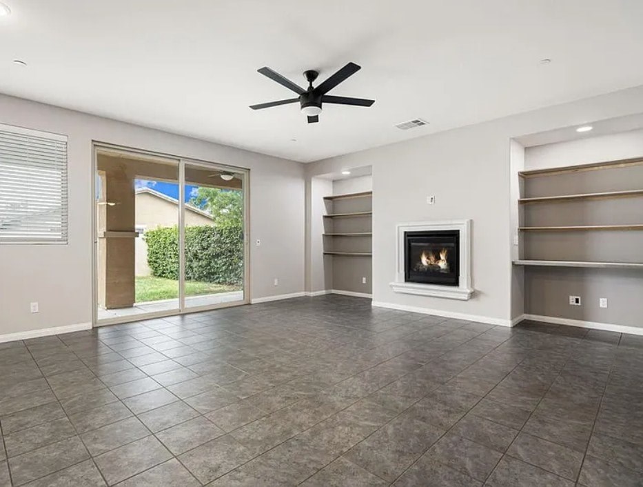 A spacious living room with a fireplace and a ceiling fan.