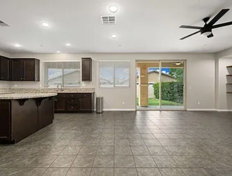 A spacious kitchen with dark brown cabinets and a marble countertop.