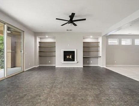 A spacious living room with a fireplace and a ceiling fan.