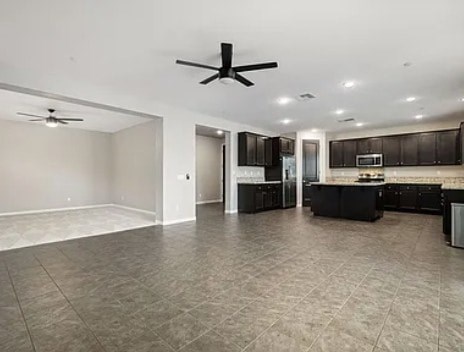 A spacious kitchen and living room with a ceiling fan.
