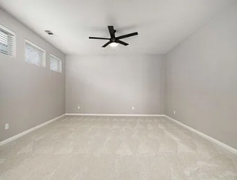 A room with a ceiling fan and carpeted floor.