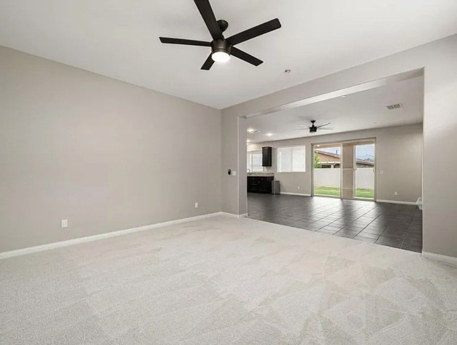 A spacious room with a ceiling fan and a carpeted floor.