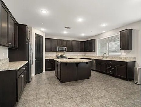A kitchen with black cabinets and a marble countertop.