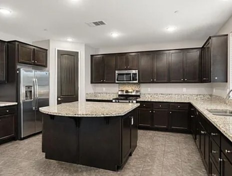 A kitchen with black cabinets and a granite countertop.