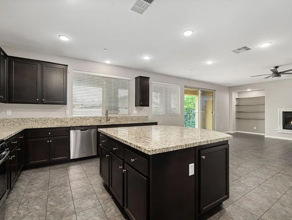 A kitchen with dark brown cabinets and a granite countertop.