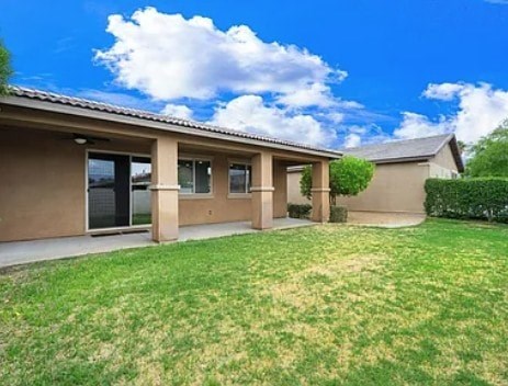 A house with a beige exterior and a green lawn.