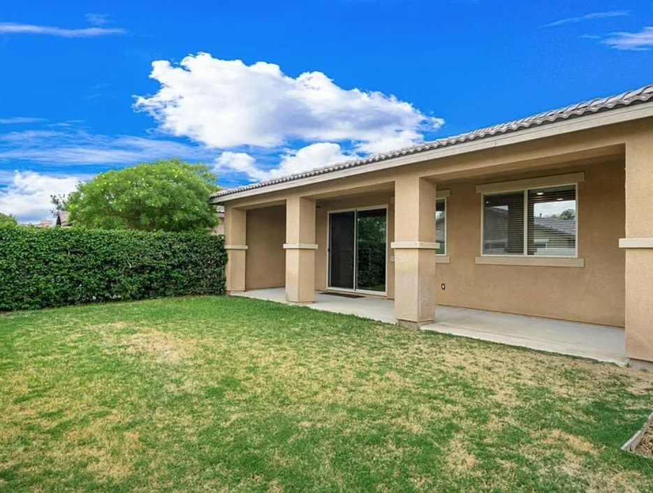 A house with a green lawn and a blue sky.
