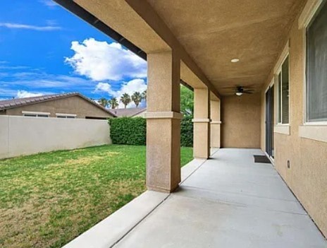 A long concrete walkway leads to a house with a covered patio.