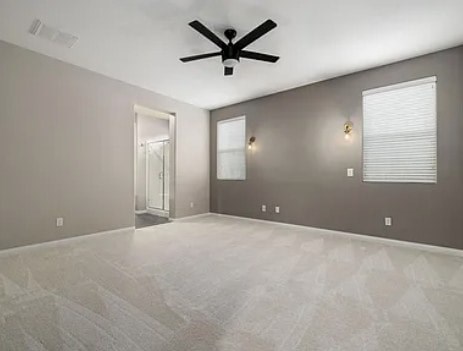 A room with a ceiling fan and a window with blinds.