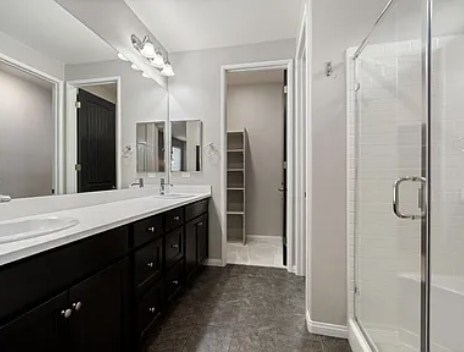 A bathroom with a sink, mirror, and shower.