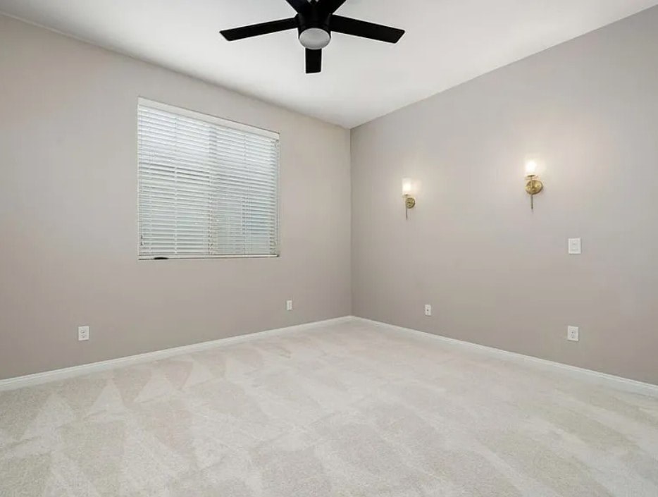 A room with a ceiling fan and two wall lights.