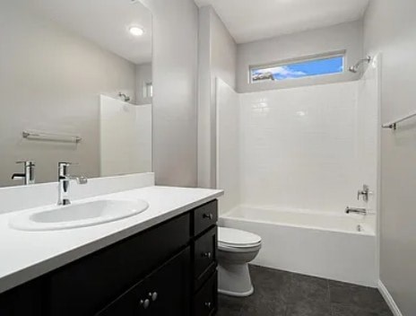 A white sink is on a countertop next to a white toilet.