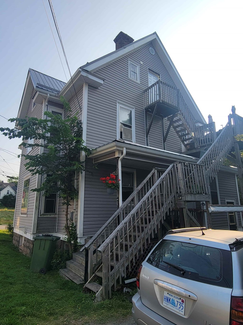 A house with a silver car parked in front of it.