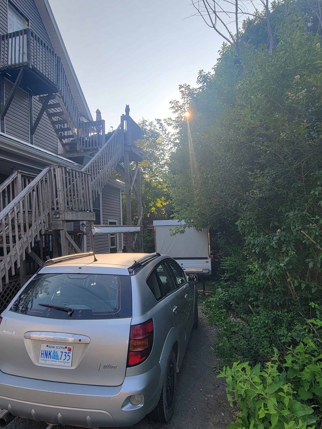 A silver car with the license plate HNK0735 is parked on a driveway.