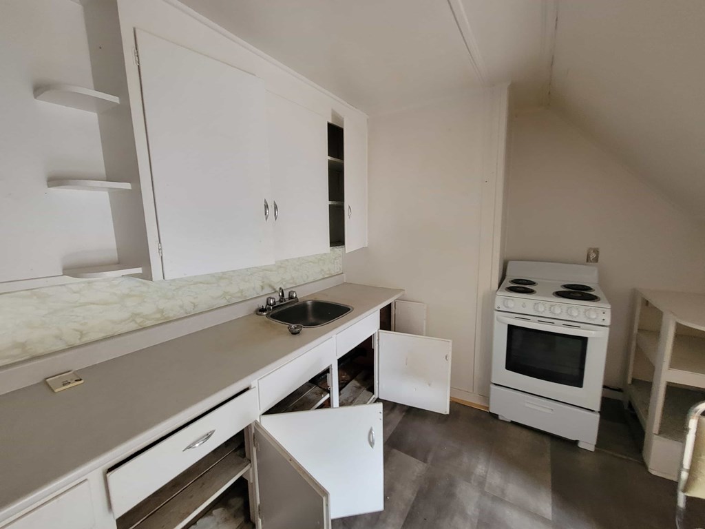 A kitchen with white cabinets and a marble countertop.