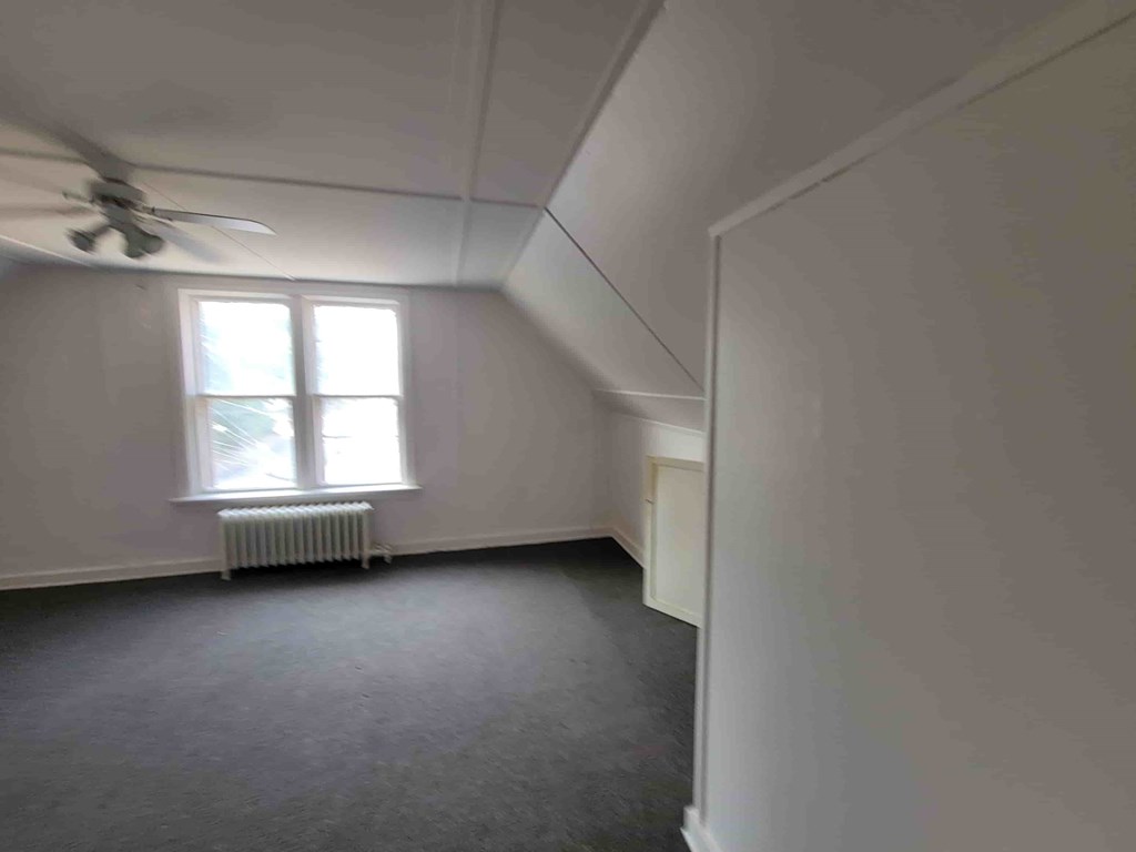 A room with a window and a fan on the ceiling.