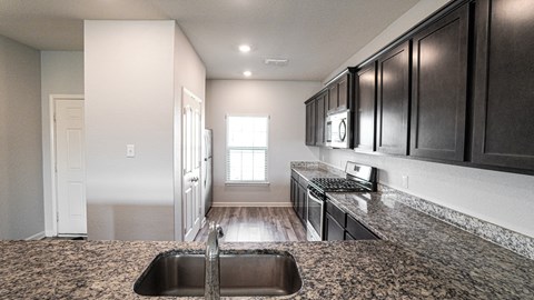 A kitchen with dark wood cabinets and a granite countertop.
