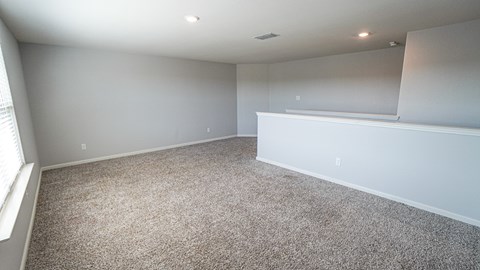 A sparsely furnished room with a carpeted floor and white walls.
