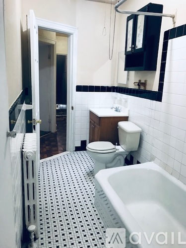 A white toilet sits in a bathroom with a white bathtub and a white sink.