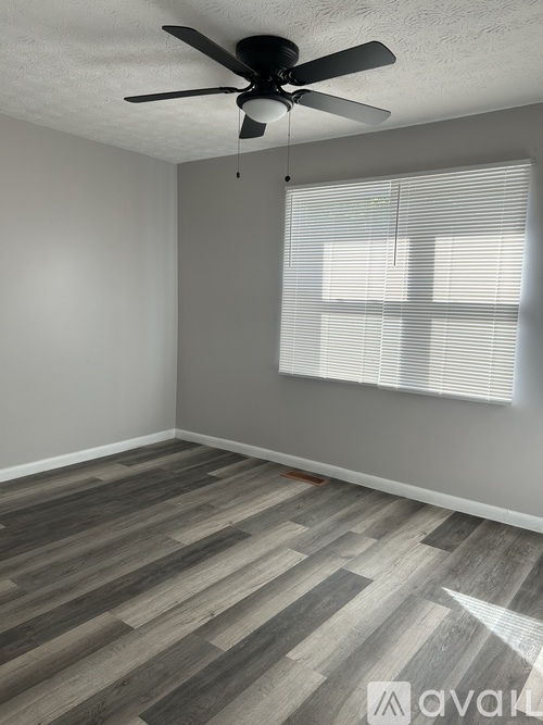A room with a ceiling fan and wood flooring.