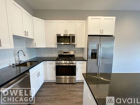 A kitchen with white cabinets and a black countertop.