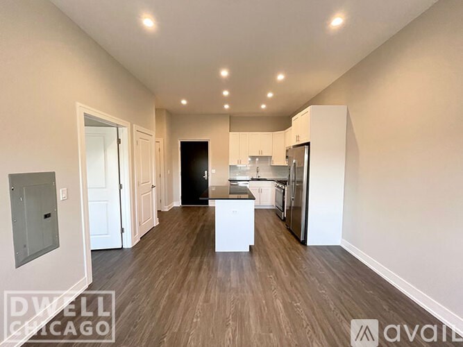 A spacious kitchen with white cabinets and a black refrigerator is available for rent.