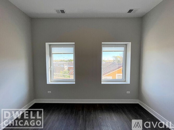 A room with two windows and a wooden floor.