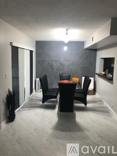 A modern living room with black chairs and a grey wall.