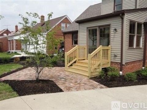 A small tree is planted in a mulched area in front of a house.