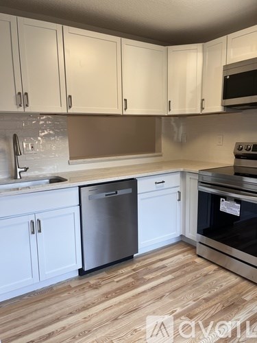 A kitchen with white cabinets and a wooden floor.